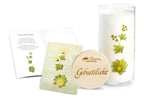 Geburtslicht, Geschenk zur Geburt, eine Kerze im Glas aus der Allgäuer Heilkräutermanufaktur. Glas mit Pflanzenaufdruck und graviertem Holzdeckel. Mit Glückwunschkarte