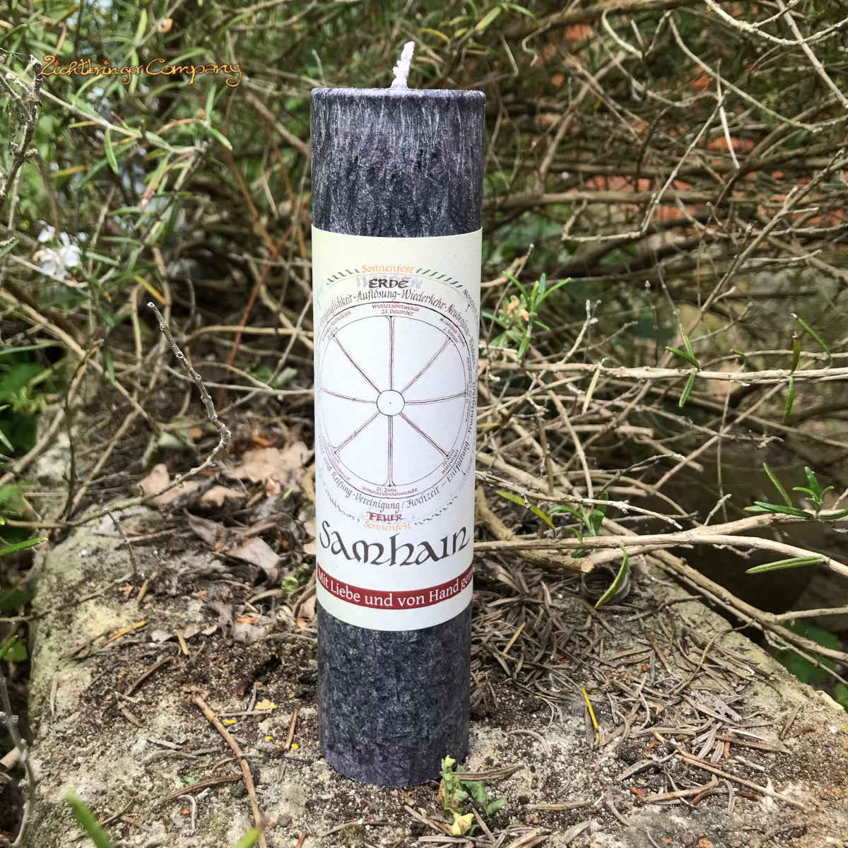Samhain Ritualkerze der Allgäuer Heilkräutermanufaktur, Farbe dunkelgrau, auf Steinmauer