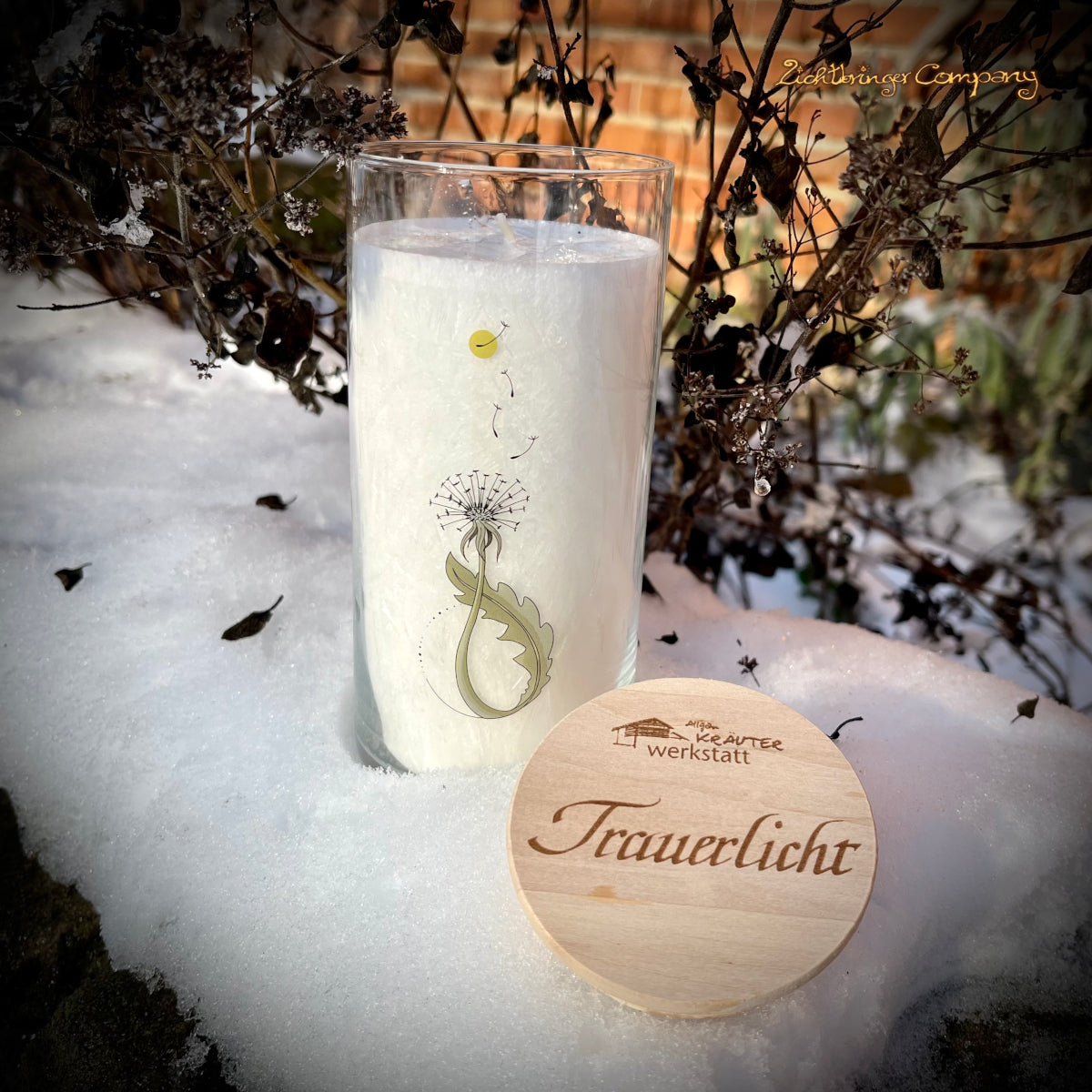 Trauerlicht Pusteblume. Allgäuer Heilkräuterkerze im Glas, Glas mit Aufdruck Pusteblume. Gravierter Holzdecke mit Aufschrift Trauerlicht. Szene im Schnee