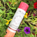 Sommersonnenwende, Ritualkerze aus der Allgäuer Heilkräutermanufaktur, in rot und orange. Im Blumenbeet